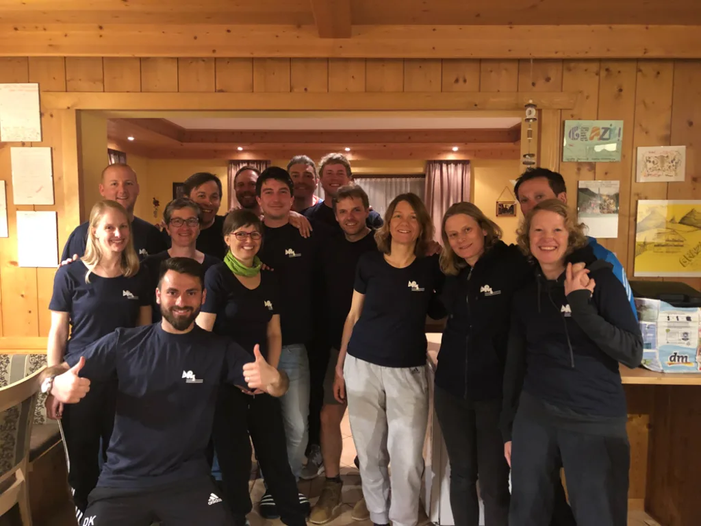 Gruppe posiert in einem holzvertäfelten Raum.